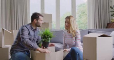 Beyaz çiftin yeni evinde karton kutuyu açmasının ön görünümü. Onlar gülümsüyor ve 4k konuşuyor