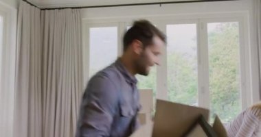 Beyaz çiftin karton kutuyu aşağı yaslayıp yeni evlerinde birbirlerini kucaklamalarının ön görünümü. Onlar gülümsüyor ve mutlu 4k
