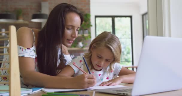白种人母亲在舒适的家里帮助女儿做作业的正面景色 他们在笔记本4K上写字 — 图库视频影像