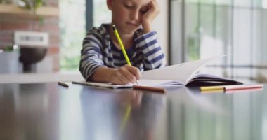 Evde mutfakta masada okuyan Beyaz çocuğun yakın çekim. O masa 4k oturuyor