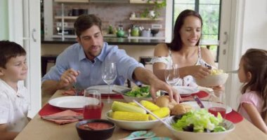 Evde yemek masasında birlikte yemek yeyen Kafkas ailesinin ön görünümü. Birbirleriyle etkileşime giriyorlar 4k