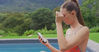 Arka bahçede cep telefonu kullanarak mayo giyen Beyaz kadın yakın çekim. O gülümsüyor ve 4k rahat