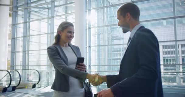 商人和女商人在办公室大堂握手 同时进行交流的镜头 — 图库视频影像