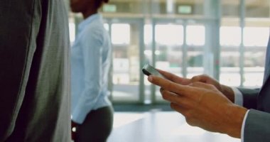 Modern bir ofiste cep telefonu kullanan beyaz iş adamının orta kesimi. Kuyrukta bekliyor. 