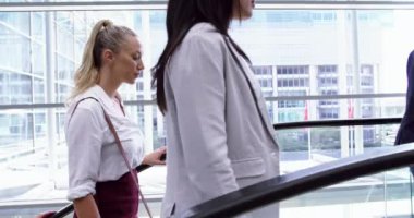 Çeşitli iş adamlarının ofis 4k 'de yürüyen merdivenle üst kata çıkmasının yan görüntüsü.