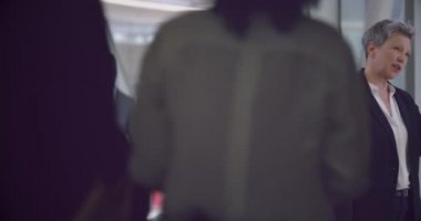 Ofisteki koridorda yürüyen çeşitli iş adamlarının dikiz görüntüsü. Birbirleriyle etkileşim içindeler.