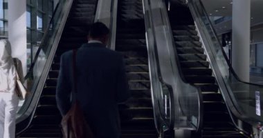 Modern bir ofiste yürüyen merdiven kullanan çeşitli iş adamlarına genel bakış. Cep telefonu kullanan bir işadamı 