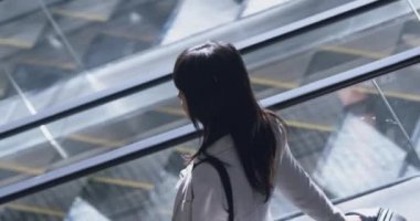 Modern ofiste yürüyen merdiven kullanan farklı iş adamlarının yüksek açılı görüntüsü. İş adamı cep telefonuyla konuşuyor. 