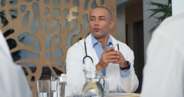 Genç melez erkek doktorun masada oturup 4K toplantısını dinlediği yavaş çekim.