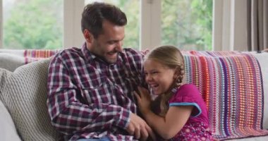 Rahat bir evde eğlenen Kafkas baba ve kızının ön görünümü. Onlar kanepede 4k oturuyorlar