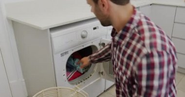 Rahat bir evde çamaşır makinesinden bez leri kaldıran Kafkas adamın yan görünümü 4k