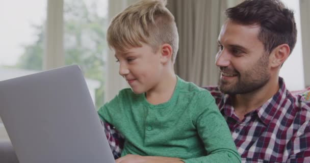 편안한 집에서 노트북을 사용하여 아버지와 아들의 정면보기 그들은 4K에 앉아있다 — 비디오