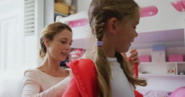 Beyaz anne yakın çekim rahat evde yatak odasında bez giyen kızı yardım. O 4k gülümsüyor