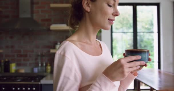 편안한 집에서 부엌에서 커피를 마시는 여성의 측면보기 그녀는 4K를 — 비디오