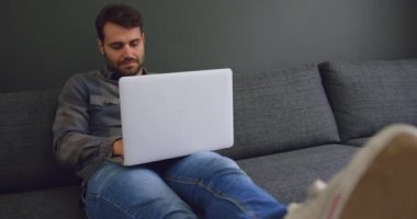 Modern bir ofiste dizüstü bilgisayar üzerinde çalışan Kafkas erkek yöneticinin ön görünümü. O kanepede 4k oturuyor