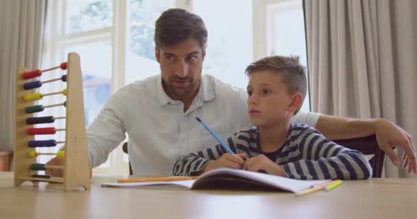 快適な家でそろばんで息子の数学を教える白人の父親の正面図 テーブル4Kに座っている — ストック動画