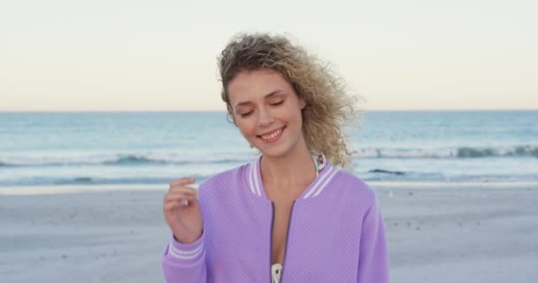 特写一个年轻的白种妇女站在海滩上微笑的相机4K — 图库视频影像