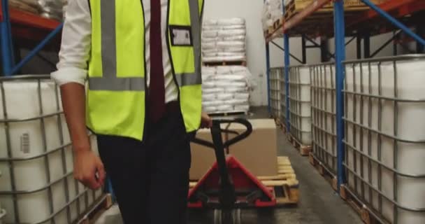 Vue rapprochée d'un jeune Asiatique tirant des boîtes sur un chariot dans un entrepôt. Ils travaillent dans un entrepôt de transport et de distribution de marchandises . 