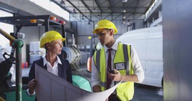 Orta yaşlı beyaz bir iş kadını ve genç bir Asyalı erkek depo yöneticisi bir depoda konuşurken ve o tutuyor büyük bir plan bakıyor ön görünümü. 4k