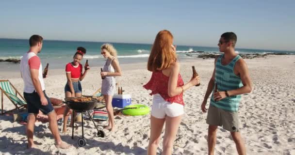 バーベキュー ビールを飲みながらビーチに立っている若い大人の友人の多民族グループの完全な長さの眺め 一緒にビーチで夏の楽しみを持っている若い友人4K — ストック動画