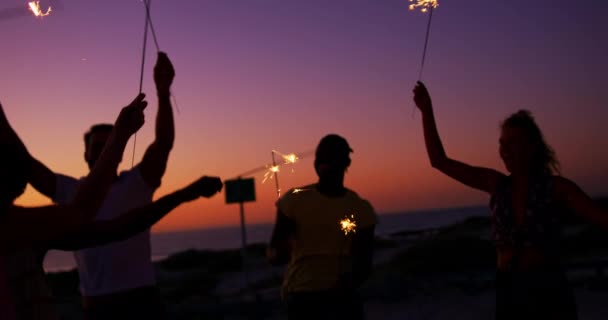 日落时分 一群多民族的年轻成年朋友在沙滩上 在周围跳舞 玩得很开心 挥舞着发光的火花 夏季日落党在海滩上与朋友有乐趣4K — 图库视频影像