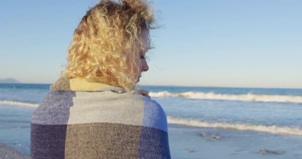 特写后视图一个年轻的高加索妇女站在海滩上穿着披肩 转身看着相机4K — 图库视频影像