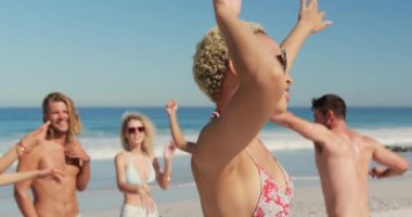 Arkadaşlarıile bir plajda dans genç bir karışık ırk kadın yakın. Genç arkadaşlar birlikte 4k plajda yaz eğlencesi