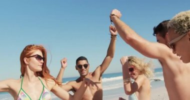 Çok ırklı genç yetişkin arkadaş grubunun, yavaş çekimde sahilde birlikte dans etmek. Genç arkadaşlar birlikte 4k plajda yaz eğlencesi