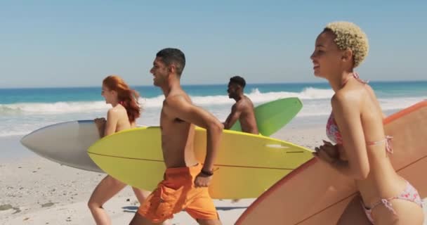 近距离的一面 一群多民族的年轻成年朋友带着冲浪板在沙滩上奔跑 年轻的朋友在沙滩上享受夏天的乐趣 一起4K — 图库视频影像