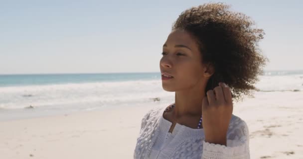 海のそばのビーチを歩く若いアフリカ系アメリカ人女性のクローズアップ 振り向くと距離4Kを見て — ストック動画
