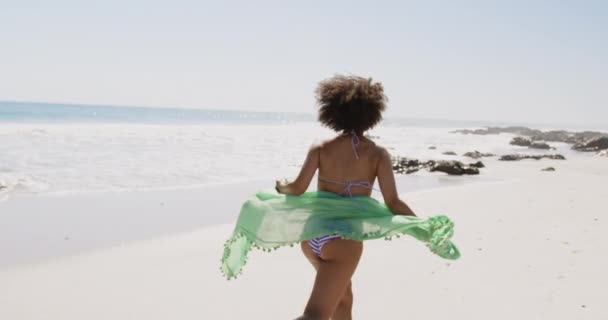 ビーチラップを持ち ビーチ4Kに沿って走っている若いアフリカ系アメリカ人女性のクローズアップバックビュー — ストック動画