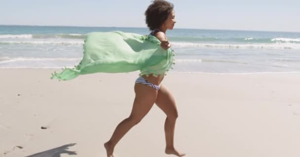 ビーチラップを持って4Kジャンプビーチに沿って走っている若いアフリカ系アメリカ人女性のクローズアップサイドビュー — ストック動画
