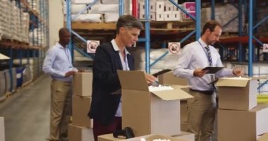 Çeşitli depo yöneticileri ve personelinin yan görüntüsü yükleme bölümünde bir teslimat için kutular hazırlıyor ve envanteri ve tablet bilgisayarı kontrol ediyor.. 