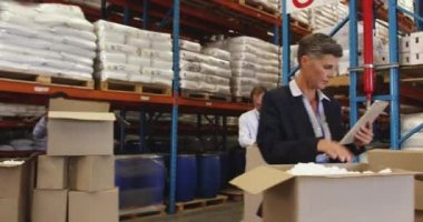 Depoda teslimat için kutu toplayan Afrikalı genç bir Amerikalı 'nın ön görüntüsünü kapatın. Arka planda meslektaşlar da teslimat için kutuları hazırlıyorlar.. 