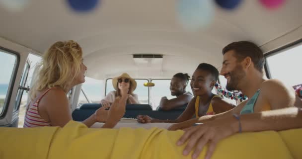 一群多民族的年轻成年男女朋友坐在露营车里谈笑风生 夏季公路旅行在露营车到海滩与朋友4K — 图库视频影像