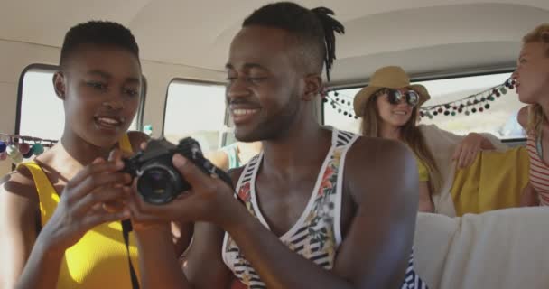 一对年轻的成年非洲裔美国夫妇看着相机 彼此交谈 面带微笑 与朋友坐在露营车里 夏季公路旅行在露营车到海滩与朋友4K — 图库视频影像