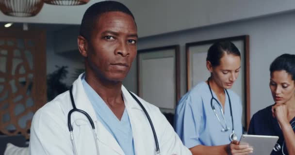 在医院的大厅里 非洲裔美国医生手挽手看着摄像机的镜头交叉地出现在眼前 女医生讨论数码平板电脑 — 图库视频影像