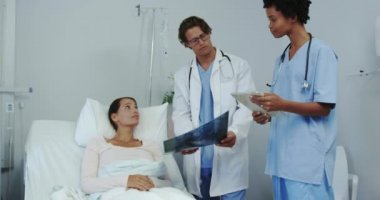 Çok ırklı erkek ve kadın doktorların koğuştaki hastalara sağlık raporu göstermesi ön planda. Konuşuyorlar ve tartışıyorlar. 
