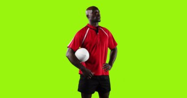 Genç bir Afrikalı Amerikalı rugby oyuncusunun canlandırması ayakta duruyor, etrafına bakıyor ve parlak yeşil bir arka planda kolunun altında bir topu tutuyor 4k