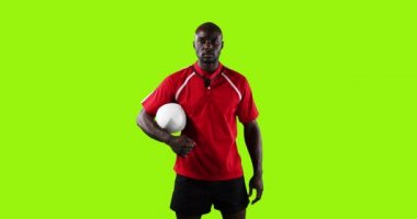 Genç bir Afrikalı Amerikalı rugby oyuncusunun canlandırması. Kameraya bakıyor ve parlak yeşil bir arka planda topu kolunun altında tutuyor. 4k
