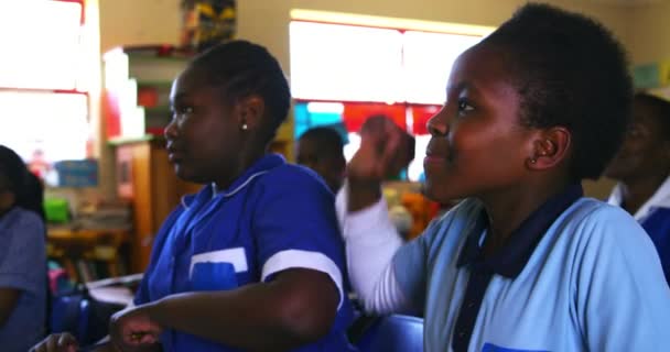 Вид Сбоку Молодых Африканских Школьниц Сидящих Партами Одна Поднимает Руку — стоковое видео