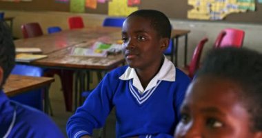 Kasabanın ilköğretim sınıfı 4k 'de ders sırasında not defterine yazan Afrikalı bir çocuğun ön görüntüsü.