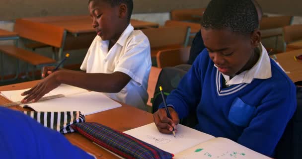两名年轻的非洲学生坐在课桌前 坐在教室前 在镇里小学四千米的教室里写作 眼前的景象令他们目瞪口呆 — 图库视频影像