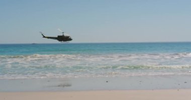 Sahilde alçaktan uçan bir helikopterin görüntüsü.