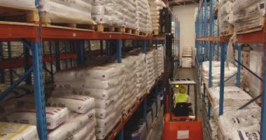 Bir depo depolama koyunda raflar arasındaki koridorda kullanılan bir forklift kamyon yükseltilmiş arka görünümü. 4k