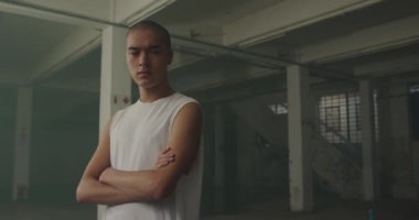 Boş bir depoda bir kalça genç karışık ırk adam Portresi, çapraz kolları ile kameraya bakıyor