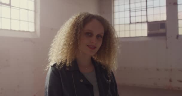 空の倉庫で腰の若い白人女性の肖像画 カメラに微笑む — ストック動画