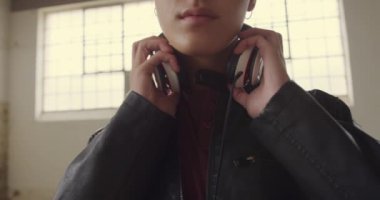 Boş bir depoda bir kalça genç karışık Yarış adam ön görünümü yakın, kulaklık koyarak