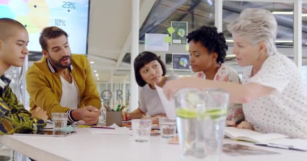 在一个现代开放式计划办公室的会议上 一群不同的创意专业人员围坐在桌旁聊天 — 图库视频影像