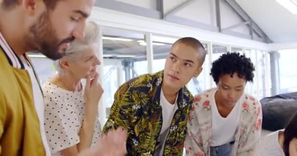 Vue de face gros plan d'un groupe de divers professionnels de la création debout autour d'un ordinateur portable en discussion dans un bureau moderne ouvert 